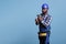 Concentrated african american builder holding cordless drill against blue background.