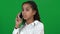 Concentrated African American teenage girl talking on the phone laughing at chromakey background. Positive happy