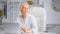 Concentrated aged lady manager in glasses sitting on large chair at table