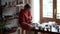 Concentrated attentive woman sits in workshop wiping items from kitchen utensils with rag and sponge