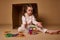 Concentrated beautiful European preschooler girl plays with lots of colorful plastic blocks constructor and building house. Fine