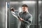 Concentrated businessman in shirt thoroughly reading the documents in the elevator. Surprised office worker is looking at papers