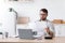 Concentrated busy mature caucasian man in glasses work with documents near laptop