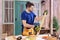 Concentrated carpenter taking measures of wooden plank on porch