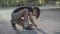 Concentrated Caucasian boy painting with chalk on asphalt