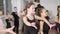 Concentrated Caucasian girl rehearsing latin ballroom dance movements with classmates in dancing school. Focused