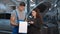 Concentrated Caucasian man explaining car repair to satisfied woman standing indoors at service station. Portrait of