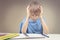 Concentrated child doing his homework at home. The boy sitting and looking in to books and notebooks.