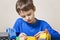 Concentrated child playing with colorful plastic construction toys at the table. Close up