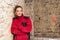 Concentrated craftswoman leaning against brick wall in bare brickwork