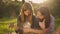 Concentrated curios teenage girl sitting in sunrays with ukulele as friend teaching playing string instrument. Portrait