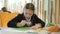 Concentrated cute schoolgirl drawing during break. Portrait of focused little Caucasian girl sitting at the table in