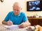Concentrated elderly man filling up papers at home table