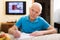 Concentrated elderly man filling up papers at home table