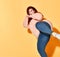 Concentrated fatty young female in jeans and sweater posing in fighting stance preparing to kick. Studio shot isolated on orange