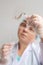 Concentrated female person raising hand while looking at hair sample, curls in a package for research by genetic research in the