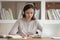 Concentrated female student studying, wearing wireless headphones.