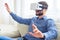 Concentrated gentleman with beard working in virtual reality glasses sitting on sofa