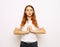 Concentrated ginger woman in white t-shirt praying with pray gesture and close eyes over white background