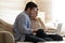 Concentrated husband and wife sitting on comfy sofa using computer