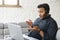 Concentrated indian man wearing headset holding virtual video conference