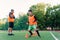 Concentrated junior soccer player running among orange cones that standing on artificial turf at stadium during workout