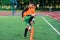 Concentrated junior soccer player running among orange cones that standing on artificial turf at stadium during workout