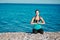 Concentrated lady meditates on beach. Sea and fresh air. Yoga and fitness concept. Healthy lifestyle idea, copy space