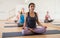 Concentrated Latina sitting in lotus pose with group of women