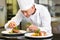 Concentrated male chef garnishing food in kitchen