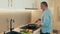 Concentrated man in casual clothes stands by the stove and stews vegetables in a frying pan. Mature man preparing