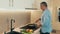 Concentrated man in casual clothes stands by the stove and stews vegetables in a frying pan. Mature man preparing