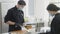 Concentrated man cutting off crust from baked cake dough as blurred woman packing muffins for delivery in kitchen. Young