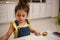 Concentrated preschooler cute Caucasian girl enjoying painting while sitting at a wooden table and mixing watercolors paints or