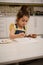 Concentrated preschooler cute little European girl enjoying painting while sitting at a wooden table and mixing watercolors or
