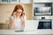 Concentrated redhead businesswoman working on laptop in bright modern office