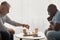 Concentrated senior man playing chess with friend, sitting at table