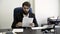 Concentrated, serious, young, bearded businessman sitting in blue leather armchair in the office and reading papers