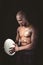 Concentrated shirtless athlete looking down while holding rugby ball