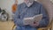 Concentrated unrecognizable old Caucasian man reading literature in nursing home. Blurred male retiree in eyeglasses