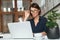 Concentrated woman in eyeglasses working with laptop computer