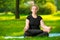 Concentrated woman oversize meditates on the lawn in the park in the lotus