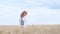 A concentrated woman in Ukrainian clothes walks through a wheat field. Blue sky background.