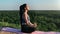 Concentrated young brunette woman yoga meditation sitting lotus position mountain peak over forest
