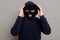 Concentrated young criminal man in a bandit mask dressing a hood, going to rob someone, trying to disguise himself more, looking