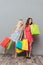 Concentrated young ladies holding shopping bags.