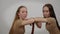 Concentrated young twin sisters looking at each other turning to camera and back. Side view portrait of serious