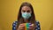Concentrated young woman in Covid-19 face mask playing fidget toy in slow motion at yellow background. front view