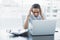 Concentrating young businesswoman working on her laptop sitting at her desk