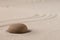 Concentration trough focus on a zen meditation stone. Round rock in sand texture background